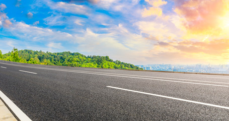 Empty asphalt road and city skyline with green mountain at sunrise in Hangzhou,China.
