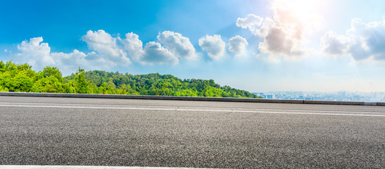 Empty asphalt road and city skyline with green mountain in Hangzhou,China.