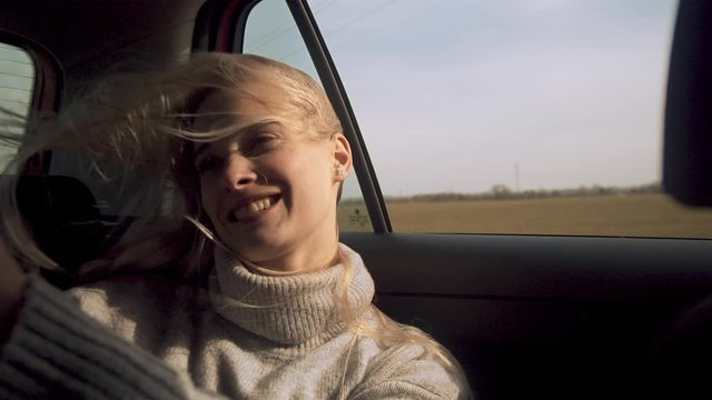Female taking selfie in car with hair in face, slow motion