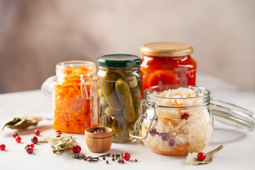 Fototapeta na wymiar Fermented preserved vegetables food concept. Glass jars with fermented, pickled and canned vegetables on kitchen table. Conservation of farm organic seasonal harvest. Healthy homemade food