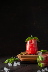 Refreshing cold summer drink watermelon slushie with basil on dark wooden background