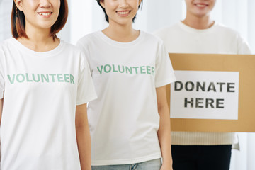 Group of smiling volunteers standing with cardboard box for donations