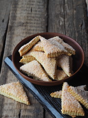 Homemade shortbread puff pastry Triangle in a brown plate on a wooden ancient background. Side view. Place for text.