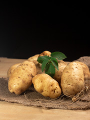Raw potato food . Fresh potatoes with leaf on wooden ,black background. selective focus
