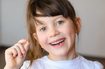 Cute preschooler showing her milk tooth fell out and her growing permanent tooth in open mouth....