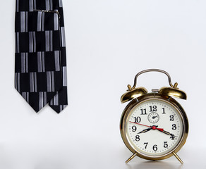 Alarm clock and men's tie on a white background. Concept - wake up, morning, business is not waiting