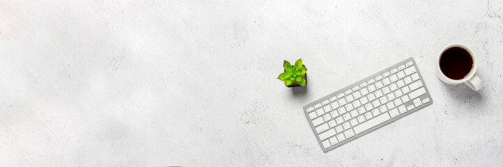 keyboard, cup with coffee and flower indoors on concrete background. Office concept, freelance,...