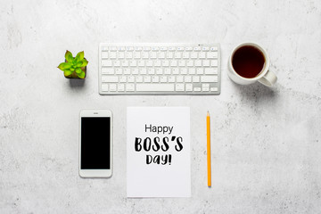 keyboard, blank paper, pencil, phone, cup with coffee and a flower indoors on a concrete background. Added text Happy Boss's Day. Office concept, freelance, work at home. Banner. Top view, flat lay