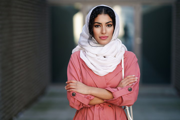 Young Muslim woman wearing hijab headscarf walking in the city center.