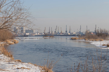 Naklejka premium Spring landscape: view of the river port and port cranes across