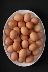 A pile of eggs on a white oval dish