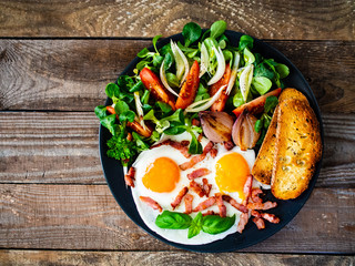 Obraz na płótnie Canvas Continental breakfast - sunny side up eggs ,toasts and vegetable salad