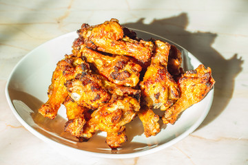 Grilled chicken drumsticks fried crispy marinated with honey is served in a flat white dish on a white background , Asian flavors and style, close-up