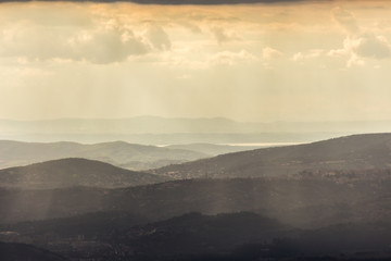 A view of Perugia city (Umbria, Italy) in the middle of hills and mist at dusk, with Trasimeno lake at the distance