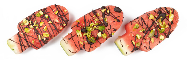 Three slices of watermelon in ice cream or popsical  shape with chocolate and pistachio nuts decoration, top view on white background