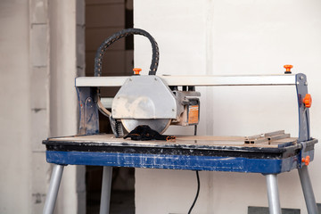 Table with electric tile cutter in interior of repair