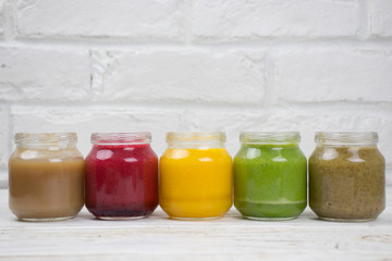 Assortment of jars with tasty baby food on wooden table. vegetable and fruit purees.
