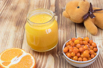 baby sea buckthorn, carrot, orange puree in a jar on a wooden table. baby food.