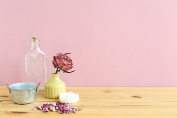 Obraz na płótnie Canvas Aroma therapy objects. Glass bottle, dried rose flower, candle on wooden table with pink background