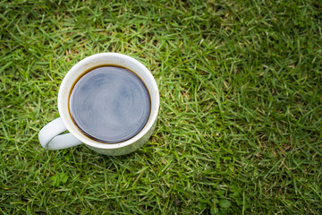 A cup of coffee on green grass