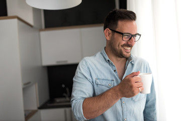 Handsome man having cup of coffee at home in the morning