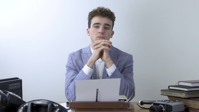 Retro 80s young man Writer look toward camera and thinks over text of  a book or a script and typing on typewriter.  author concept.