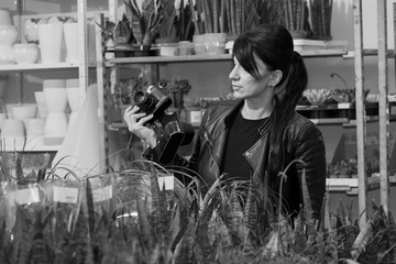 beautiful girl in a black leather jacket photographs flowers and decorations in a flower shop, with a traditional camera