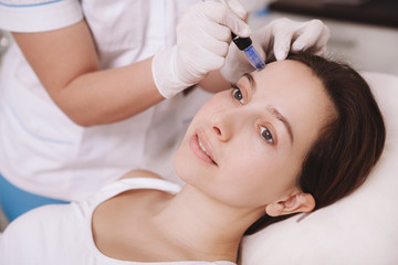 Unrecognizable cosmetologist using dermapen on female client, doing mesotherapy procedure