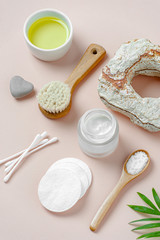 Accessories, cream and natural cosmetics for body care on a light pink background.