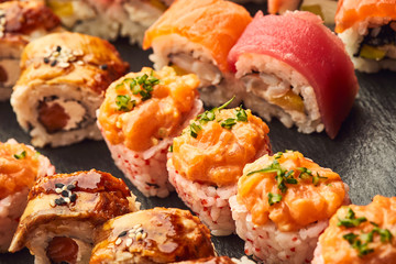 Various kinds of sushi roll set served on black stone. Japanese food