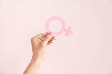 Female hand with symbol of woman on color background. Concept of feminism