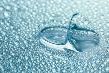 Contact lenses and water drops on color background
