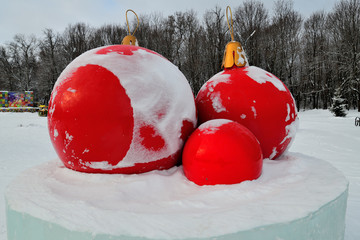  bright red christmas balls on an ice pedestal in a city park