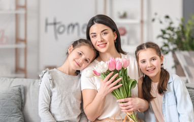 Little girls greeting their mom with Mother's Day at home