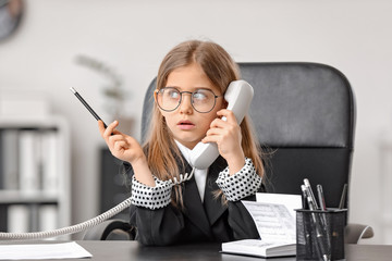Little businesswoman talking by telephone in office