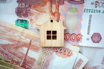 Mortgage, insurance, buying and rent, real estate business concept. Small wooden house toy on money rouble banknotes background top view