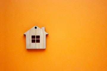 House, insurance and mortgage, buing and rent concept. Small wooden house toy on orange background...