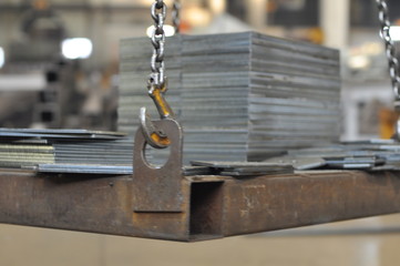 Crane hook. Lifting and moving a metal pallet with parts in a workshop.