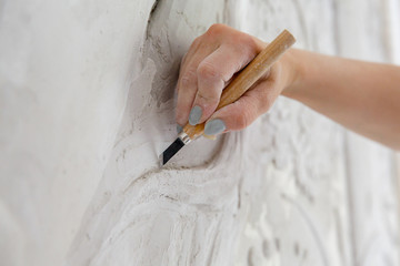 Workflow, female hand with a chisel carves a bas-relief pattern