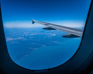 Fototapeta na wymiar View of the wing of an airplane flying over the mountains and the sea