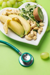 Plate with healthy products and stethoscope on color background
