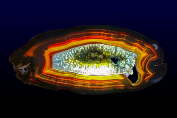 Polished slice of Agate and Quartz, isolated on a dark background. 