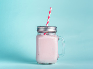 strawberry smoothie in mason jar glass on blue