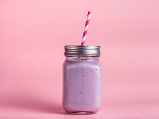 blueberry smoothie in mason jar glass on pink