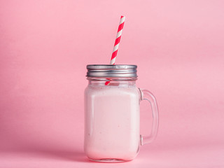strawberry smoothie in mason jar glass on pink