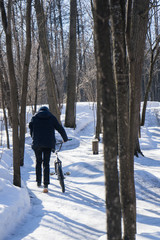 bmx rider walks into the distance with a bike in winter