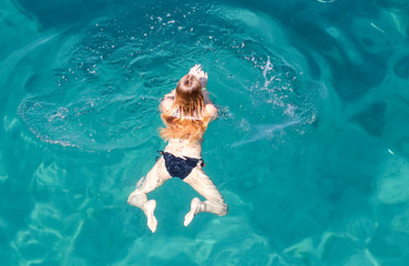 A girl swims in the blue water of the sea