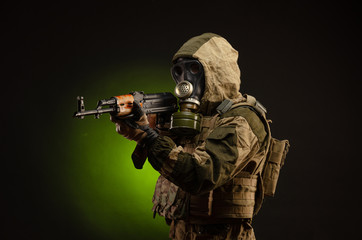 soldier Stalker saboteur in military uniform with a Kalashnikov rifle on a dark background in a gas...