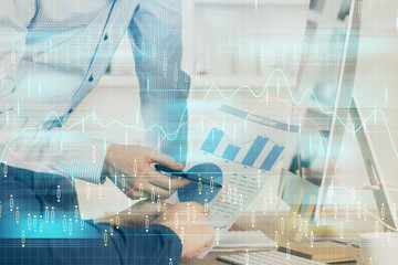 Double exposure of chart with businessman typing on computer in office on background. Concept of hard work.