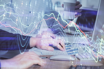 Multi exposure of chart with man typing on computer in office on background. Concept of hard work.